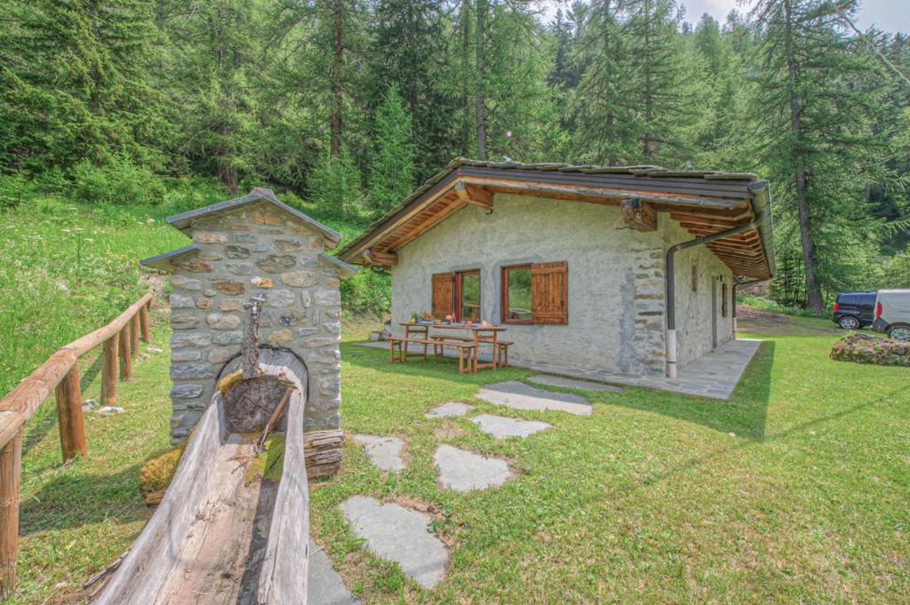 una piccola casa in pietra in un cortile con una recinzione in legno di Baita Girasole Val Veny a Courmayeur