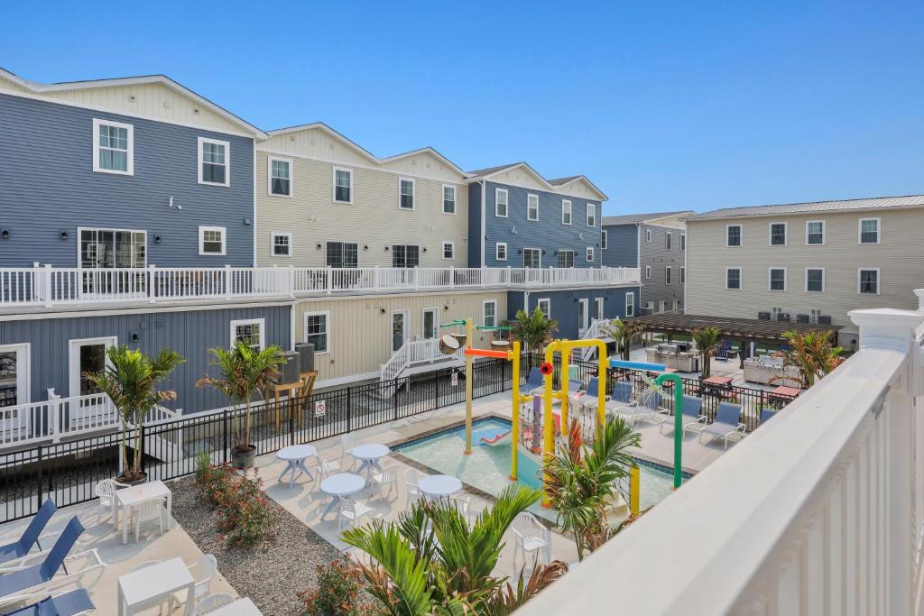 uma vista para uma piscina com um parque infantil e edifícios em Oasis by Seaport Stays em Wildwood