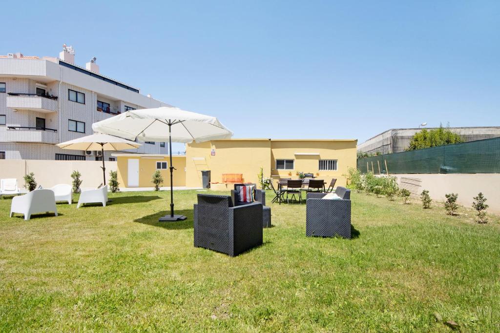 a yard with chairs and an umbrella and a building at Pontes Guest House in Arcozelo