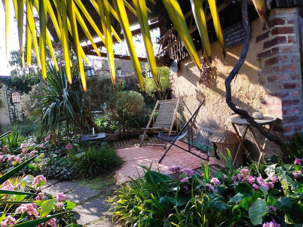 einen Garten mit einem Stuhl und einigen Pflanzen und Blumen in der Unterkunft Le Jardin Yuccas - Cosy cottage in the Loir& Loire Valleys in La Chapelle-aux-Choux