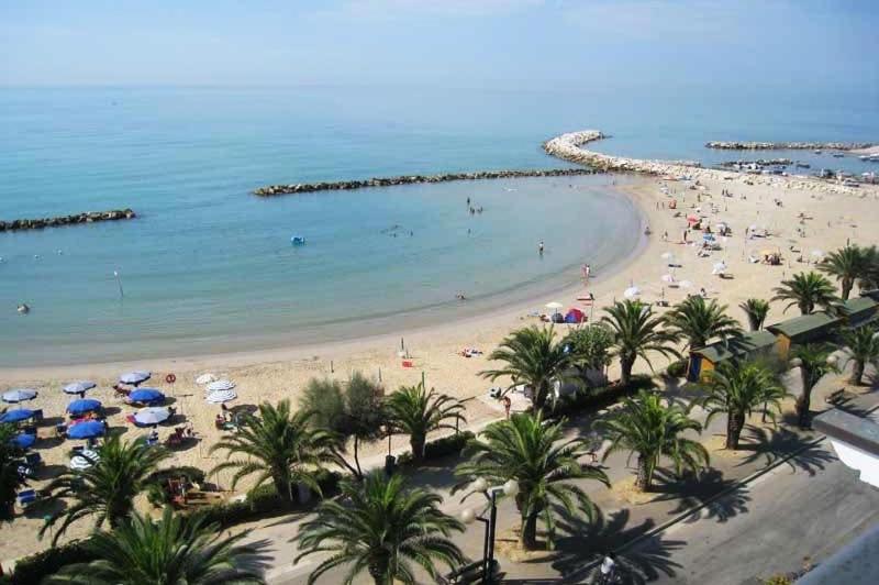 a beach with people and umbrellas and the ocean at Casa Vacanze MARE BOOM in Martinsicuro