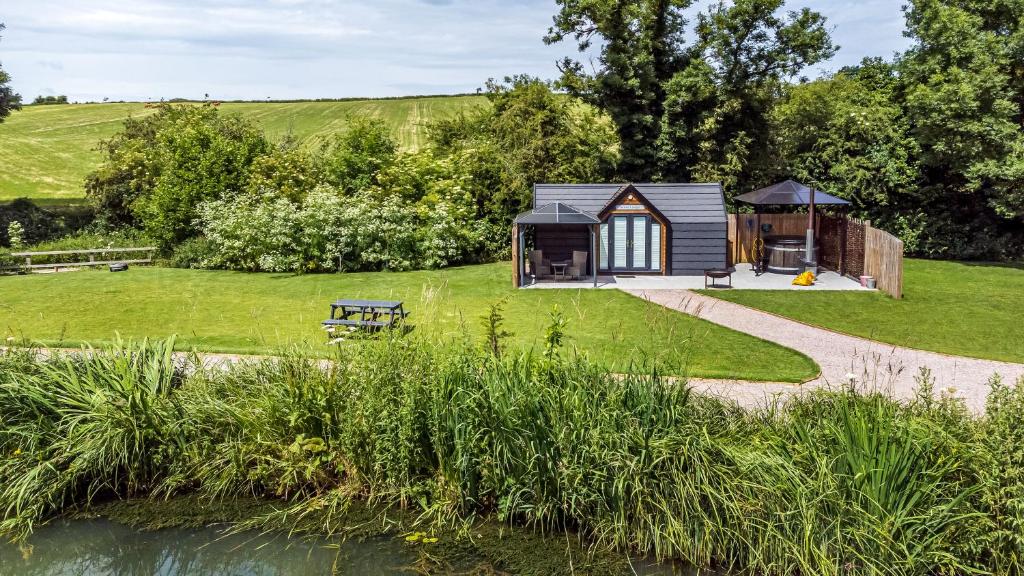 a cabin in the middle of a garden with a pond at Acorn Lodge At Bridge Lake Farm & Fishery in Banbury