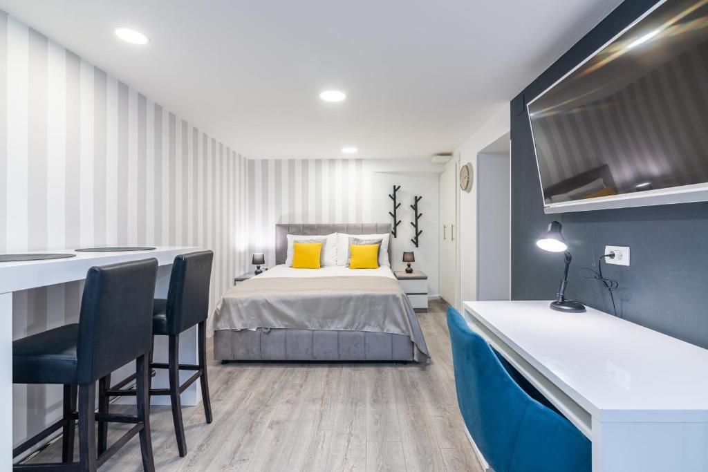 a bedroom with a bed and a desk and chairs at Small, sweet & cosy apartments in Rijeka