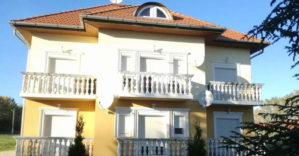 een groot geel huis met een balkon bij Szaffária Apartman Kehidakustány in Kehidakustány