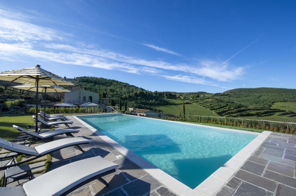a swimming pool with chairs and an umbrella at Villa il Giardino - Homelike Villas in Greve in Chianti