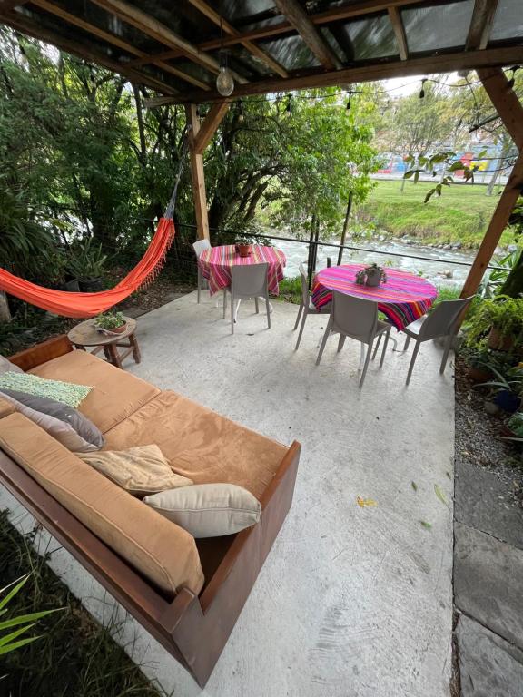 eine Terrasse mit einer Hängematte sowie einem Tisch und Stühlen in der Unterkunft Apartamentos Otorongo Cuenca Ecuador in Cuenca