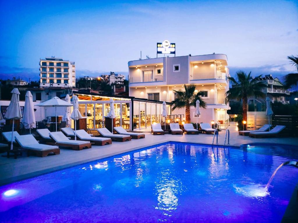 ein großer Pool mit Stühlen und ein Gebäude in der Unterkunft Blue Water Hotel Ksamil in Ksamil