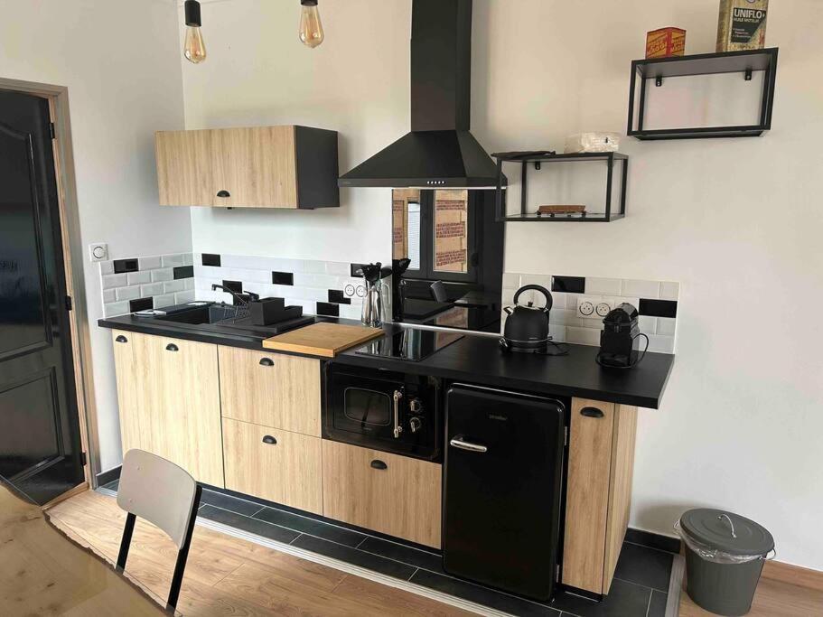 a kitchen with a black counter and a stove at Le Refuge de la Gravière in Charleville-Mézières