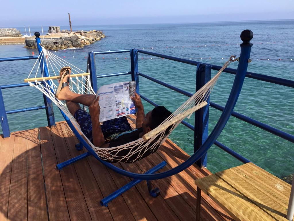 Een man in een hangmat die een krant leest. bij Manolya Hotel in Kyrenia