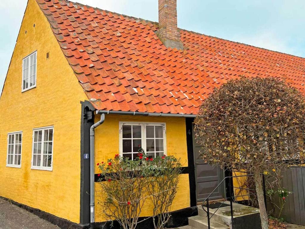 ein gelbes Haus mit orangefarbenem Dach in der Unterkunft Holiday home Svaneke LVI in Svaneke