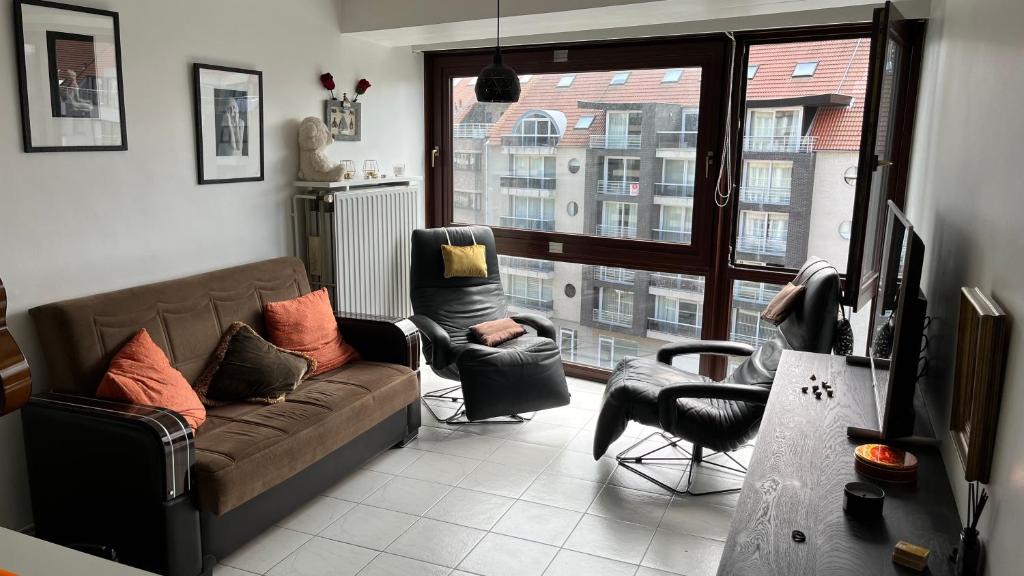 sala de estar con sofá, 2 sillas y ventana en Istamboul Heist beach en Knokke-Heist