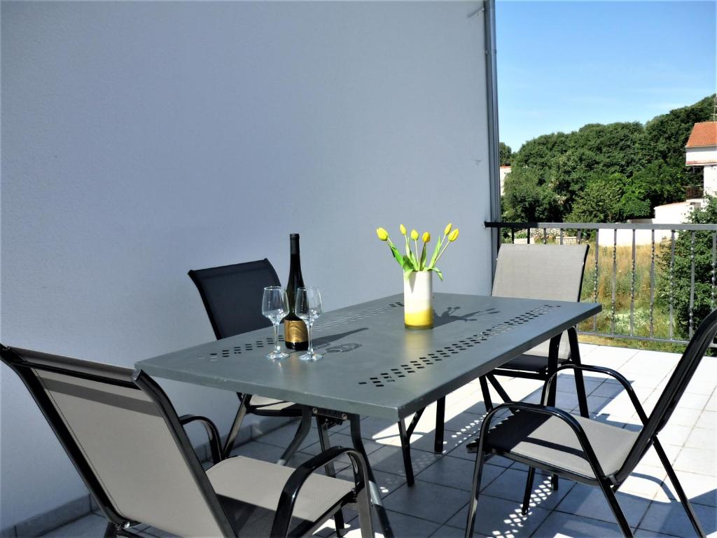 a table with wine glasses and flowers on a balcony at Cozy place in Dugopolje