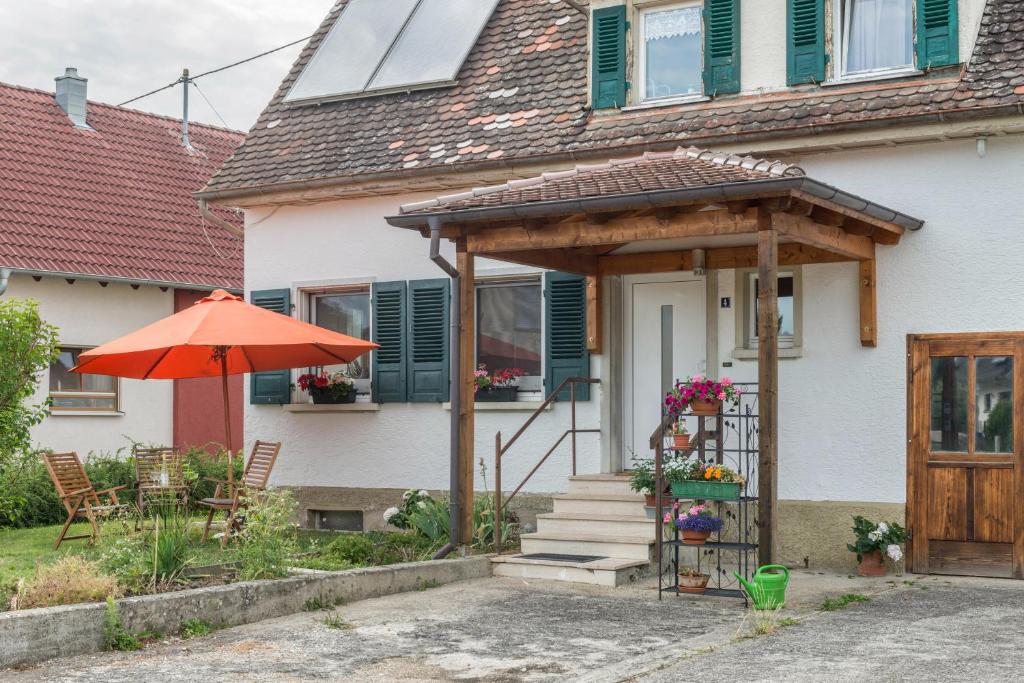 ein Haus mit einem Sonnenschirm und einer Veranda in der Unterkunft Landhausappartment in Bermatingen