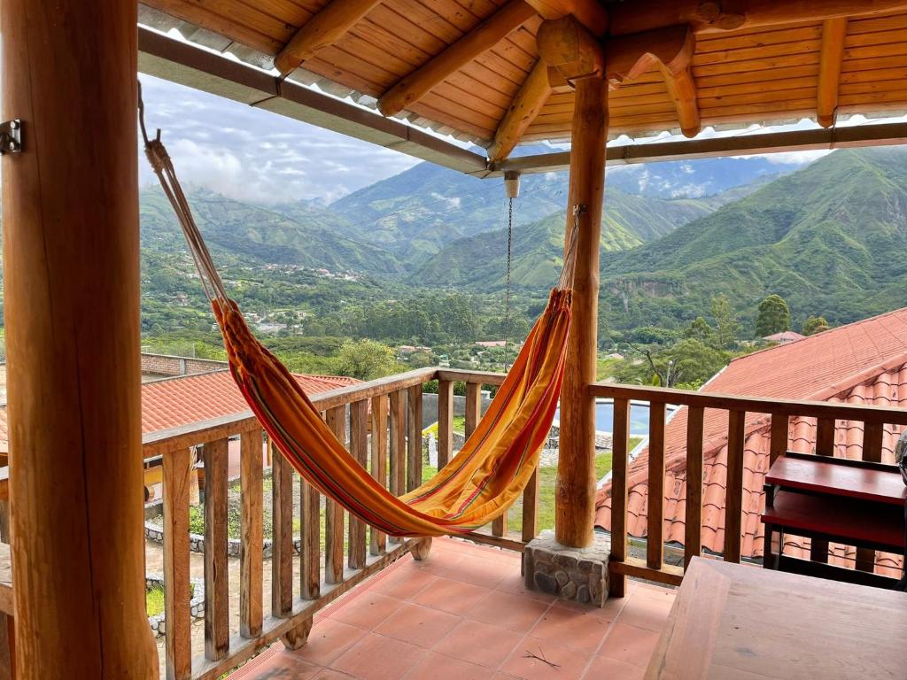 a hammock on a porch with a view of mountains at Vistabamba Ecuadorian Mountain Hostel in Vilcabamba