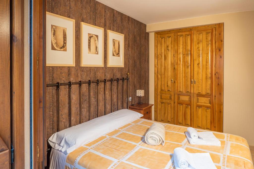 1 dormitorio con 1 cama y pared de madera en La Borda de Marco, en Gavín