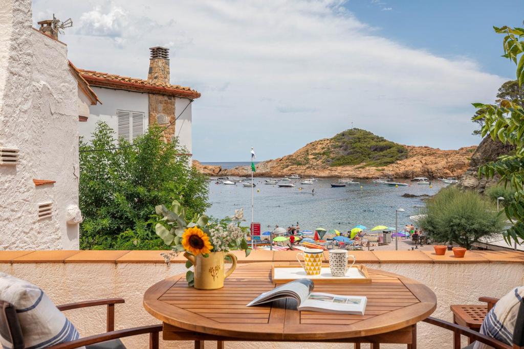 a table with a book on a balcony with a view of a beach at Flateli Sa Tuna 4 in Begur