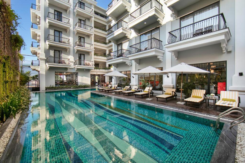 una piscina de hotel con sillas y sombrillas en Silkian Hoian Boutique Hotel & Spa en Hoi An