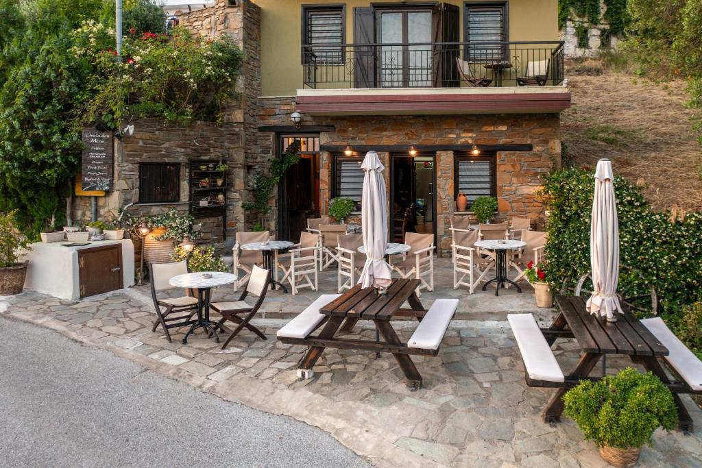 un patio avec des chaises, des tables et des parasols en face d'un bâtiment dans l'établissement Oreiades Guesthouse, à Parthénon