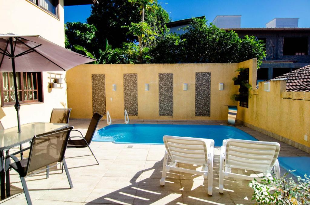 a patio with a table and chairs and a pool at Casa com Piscina para 12 hóspedes, 7 minutos da Praia no Campeche HY3097 in Florianópolis