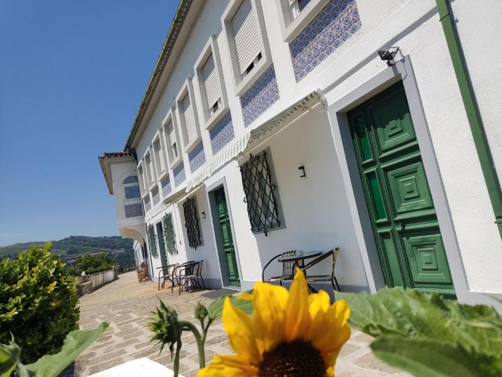 a sunflower in front of a building with a green door at Casa da Real Companhia in Lamego