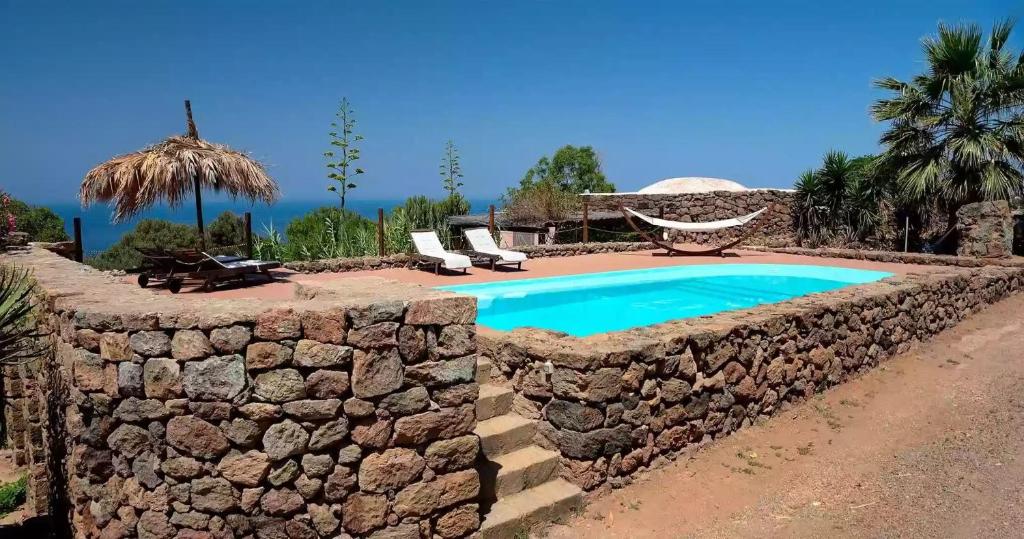 una pared de piedra alrededor de una piscina en un complejo en Dammusi Barone, en Pantelleria