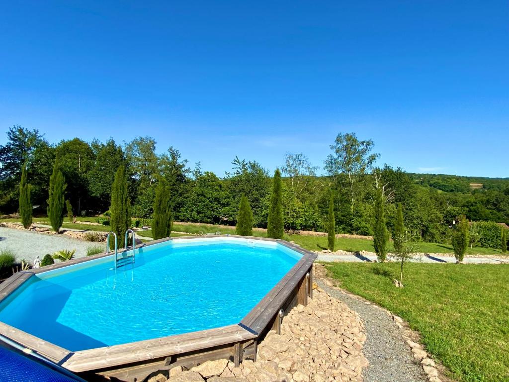 a swimming pool in a yard with trees and a field at Maison De Lavende in Bessines-sur-Gartempe