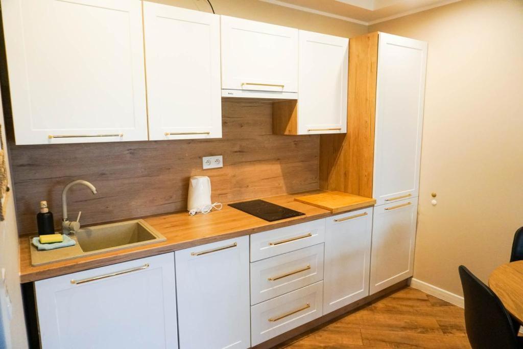 a kitchen with white cabinets and a sink at ŁAJBA KAPITANA WYPOCZYNKOWA ROWY in Rowy