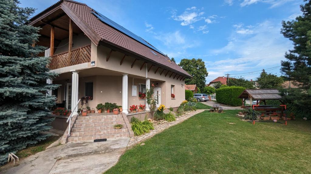a house with a porch and a grass yard at Virágos Apartman Balatonszemes in Balatonszemes