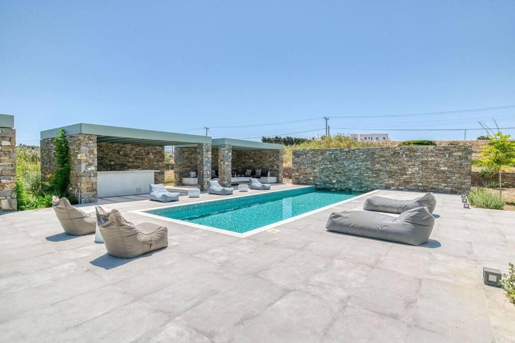 a swimming pool with couches and chairs next to a building at Villa Xifara - Seafront in Santa Maria