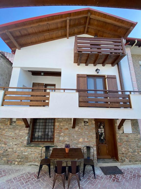 a house with a wooden table and a balcony at Martinis House in Pefkochori