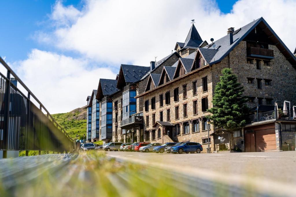 un grand bâtiment avec des voitures garées devant lui dans l'établissement Snö Villa de Sallent 4, à Formigal