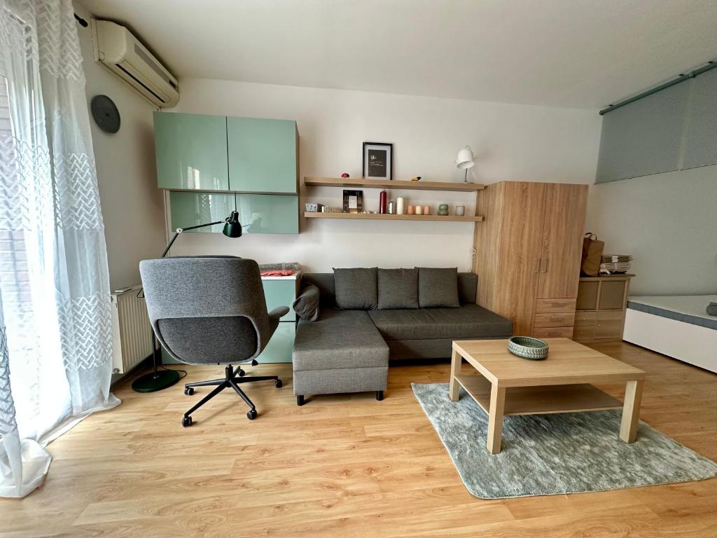 een woonkamer met een bank, een stoel en een tafel bij S3 Residences Ilka Studio Serviced Cozy Appartment in Boedapest