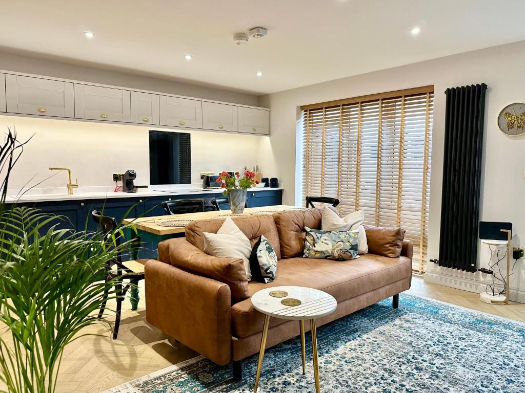 a living room with a brown couch and a kitchen at 6 The Feather in Ripon