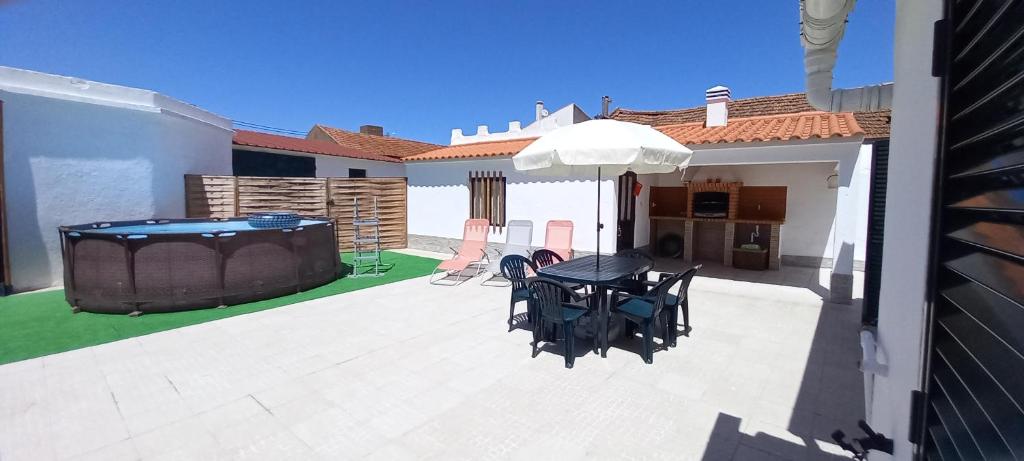een patio met een tafel en een parasol bij Murta's Home in Cadaval