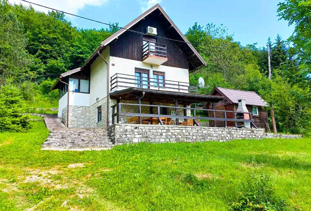 una casa grande en una colina con un campo verde en Plitvice RH Hostel Rooms, en Jezerce