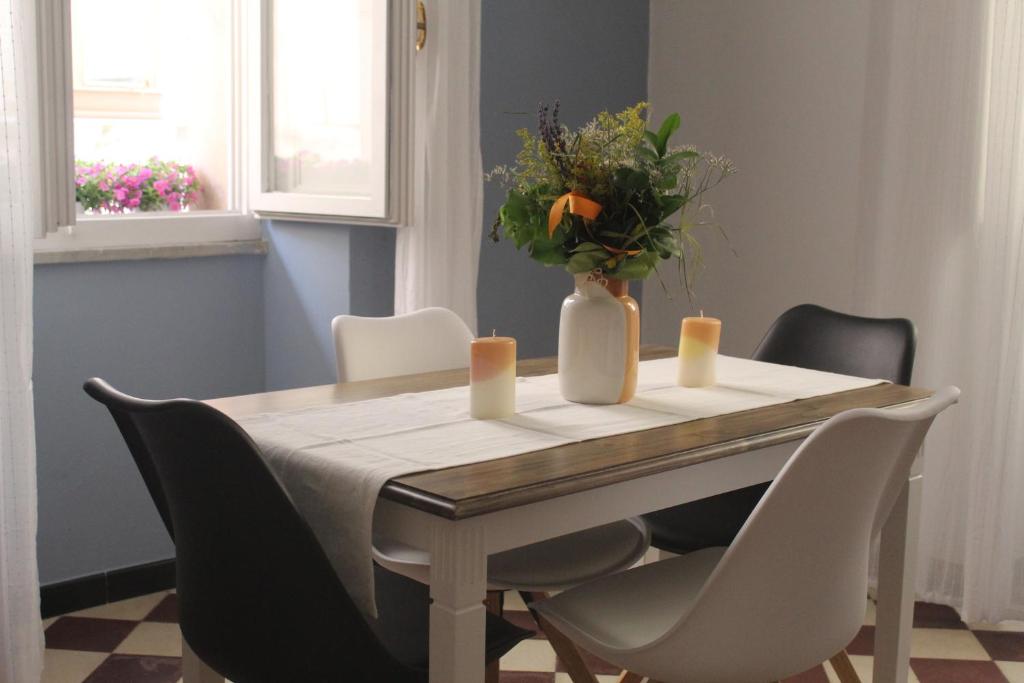 - une table à manger avec des chaises et un vase fleuri dans l'établissement Suite al castello, à Sassari
