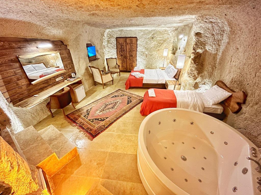 a bathroom with a tub and a bedroom with a bed at Asma Altı Cave Suit's in Nar
