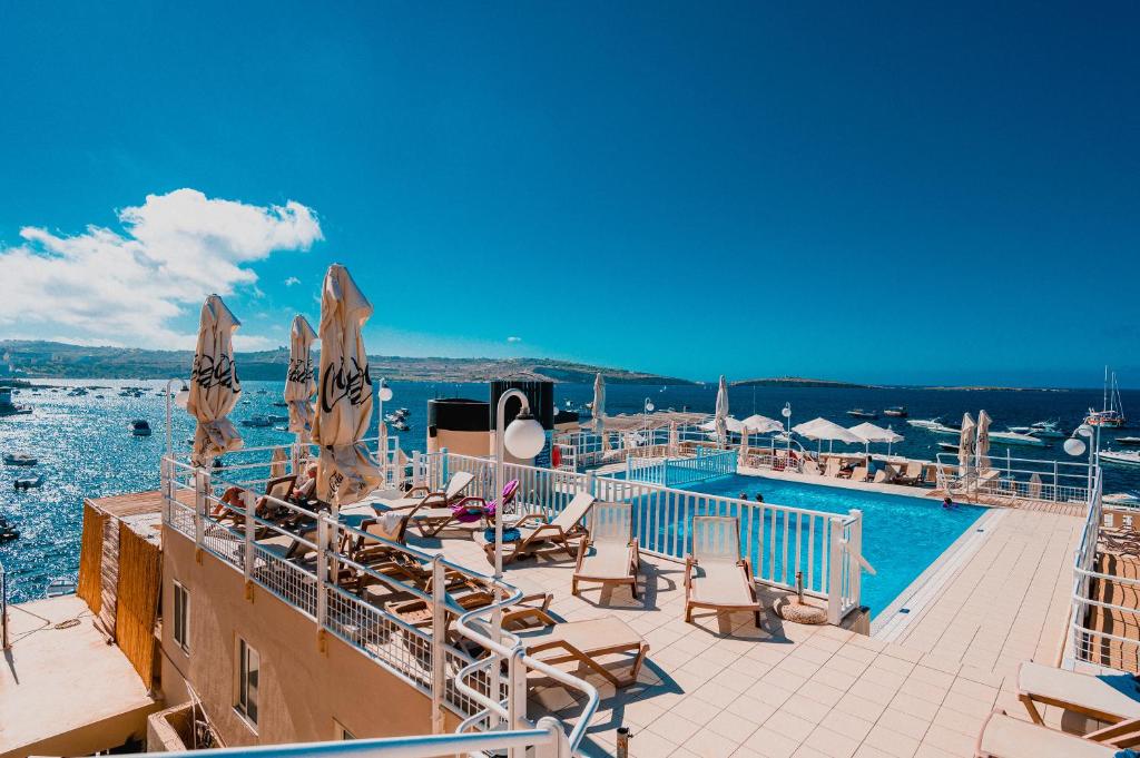 a swimming pool with chairs and umbrellas on a cruise ship at Gillieru Harbour Hotel in St Paul's Bay