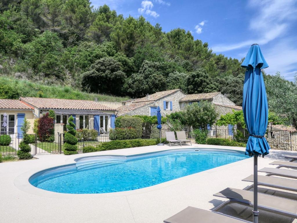 a swimming pool with a blue umbrella and chairs at Côté Lavande in Crestet