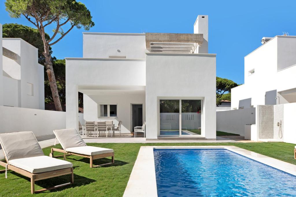 een witte villa met een zwembad en een gazon bij Villa Santa Clara 21c in Chiclana de la Frontera