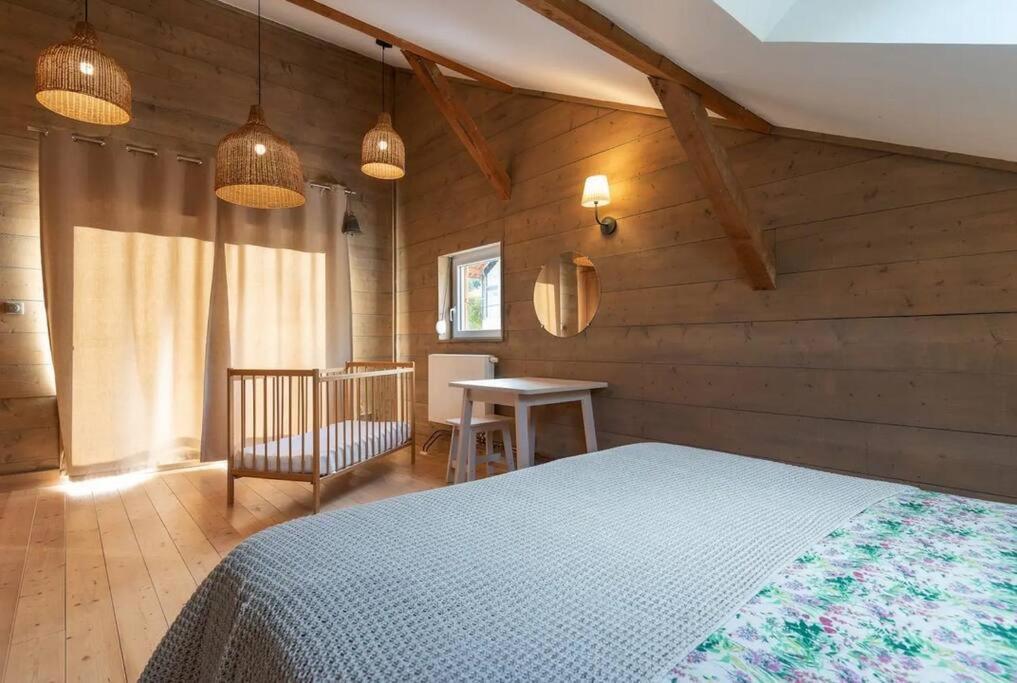 1 dormitorio con cama, mesa y luces en La Chaume des Xettes / 10-14 pers SPA - Vue Lac, en Gérardmer