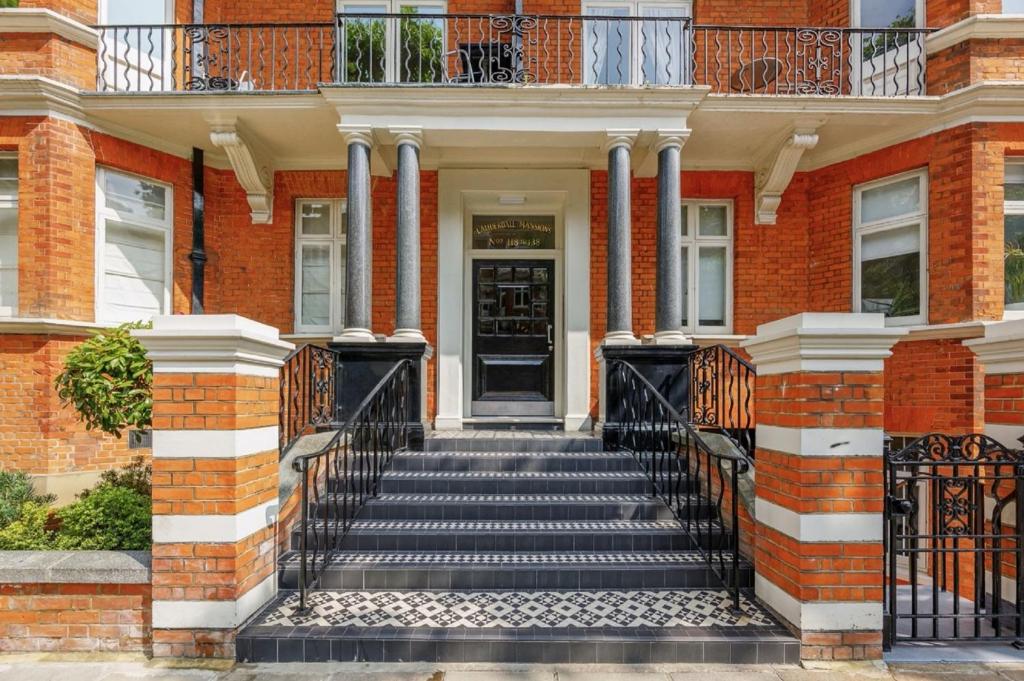 une maison en briques avec des escaliers menant à la porte d'entrée. dans l'établissement HYDE PARK, OXFORD STREET, PADDINGTON, BEAUTIFUL 3 BEDROOMS,BALCONY, 2 BATH, MANSION BLOCK, MAIDA VALE, W9 NW8 LORDs CRICKET, à Londres