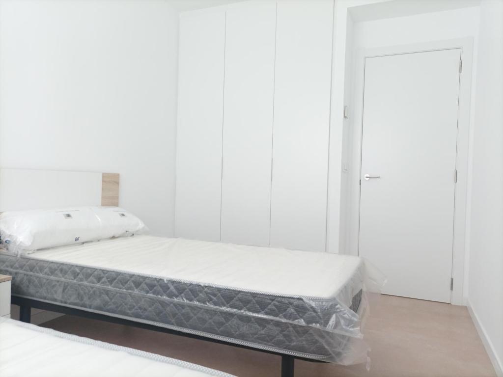 a bed in a room with a white wall at Residencial El Trenet 2A in Benicàssim