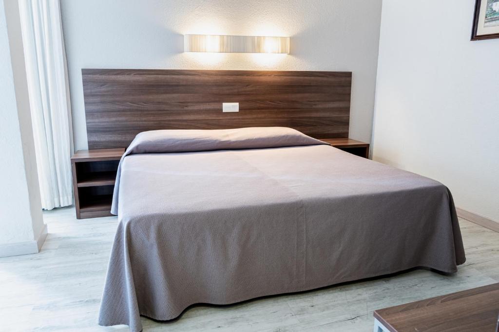 Un dormitorio con una cama grande con cabecero de madera. en Espanya - 30º hotels, en Calella