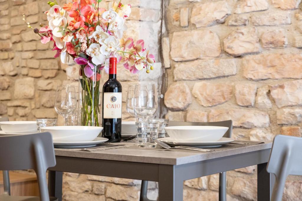 een tafel met een fles wijn en een vaas met bloemen bij Loft nel cuore di Assisi - 50 mt da Carlo Acutis in Assisi