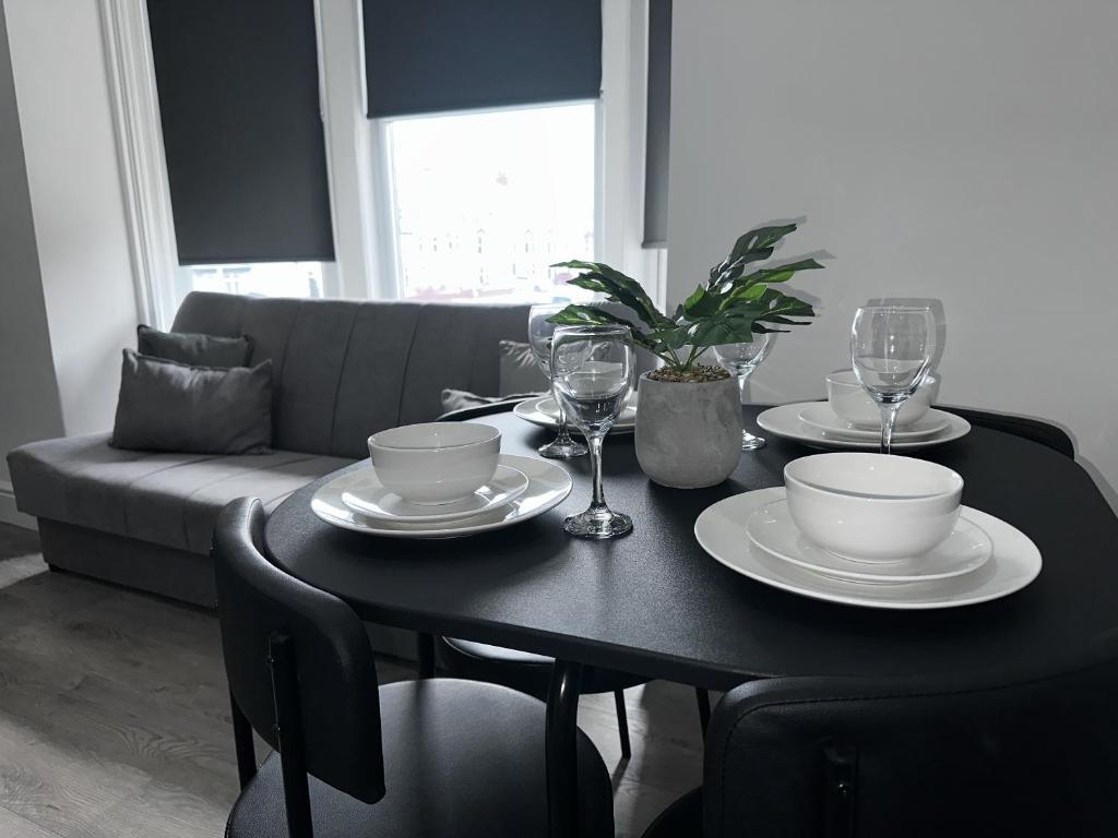 a black table with plates and glasses and a couch at new osborne luxury Hottub and jacuzzi suites in Blackpool