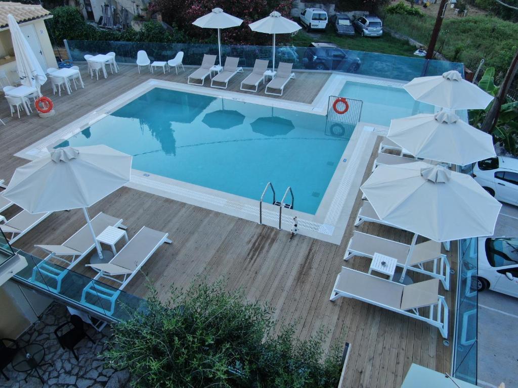 an overhead view of a swimming pool with chairs and umbrellas at Passas Mare Apartments & Studios in Benitses