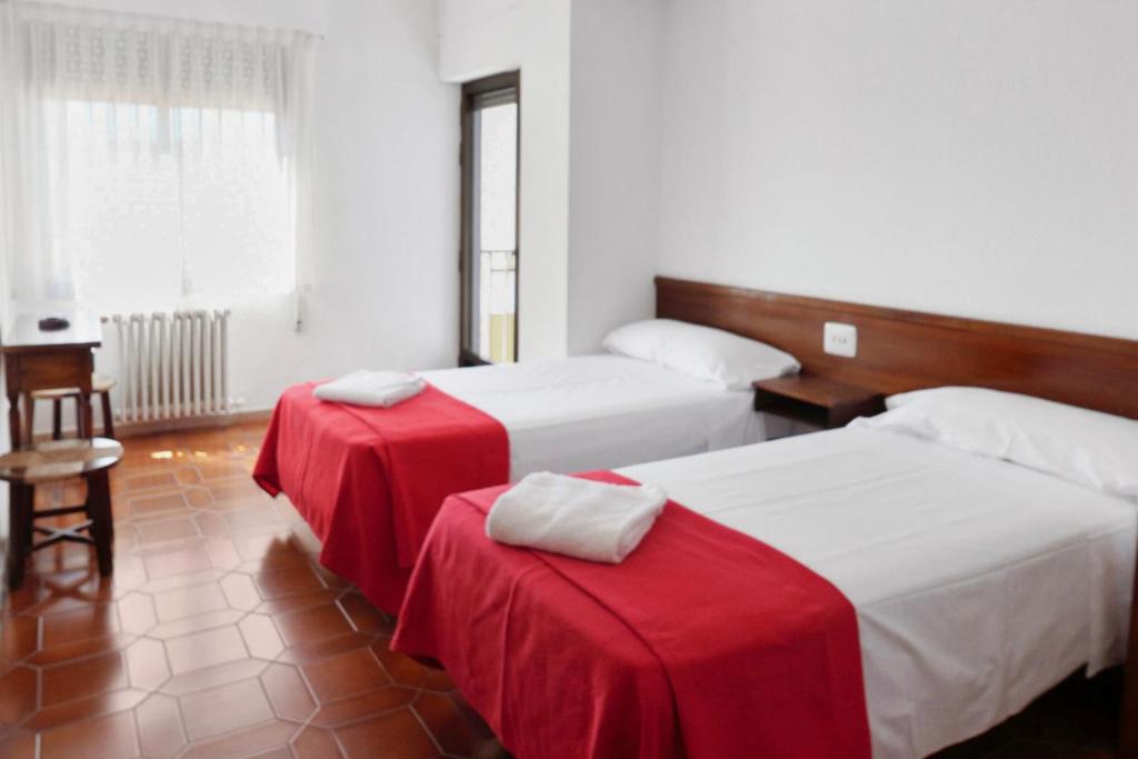 2 camas en una habitación con sábanas rojas y blancas en Hostal La Torre en Benicàssim