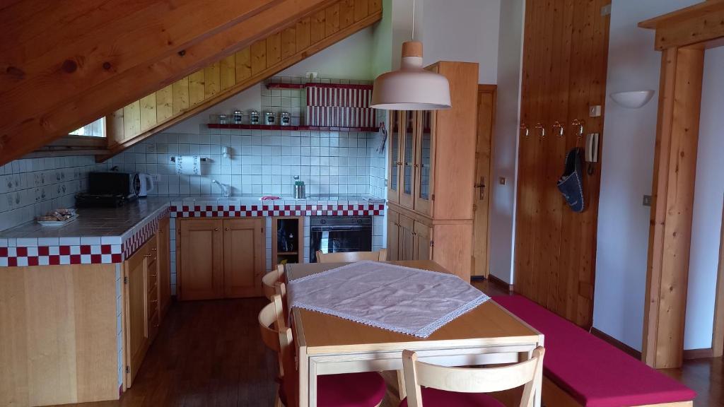 una cocina con una mesa pequeña y una cocina con armarios de madera. en Deliziosa mansarda con vista Dolomiti en San Vito di Cadore