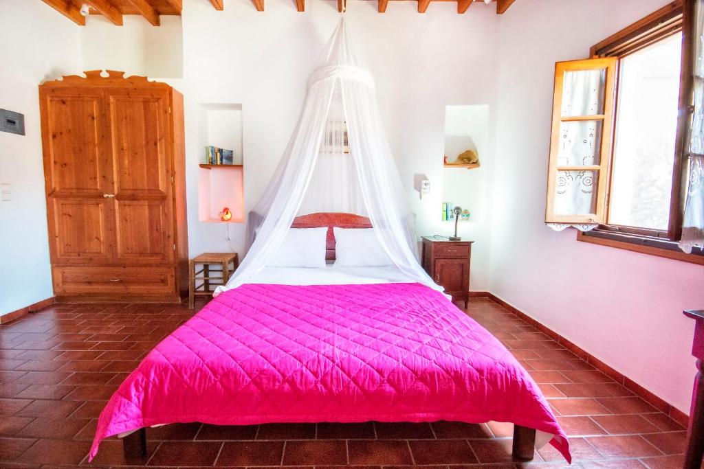 sypialnia z różowym łóżkiem z białym baldachimem w obiekcie Siroco Patmos Agriolivadi w mieście Patmos
